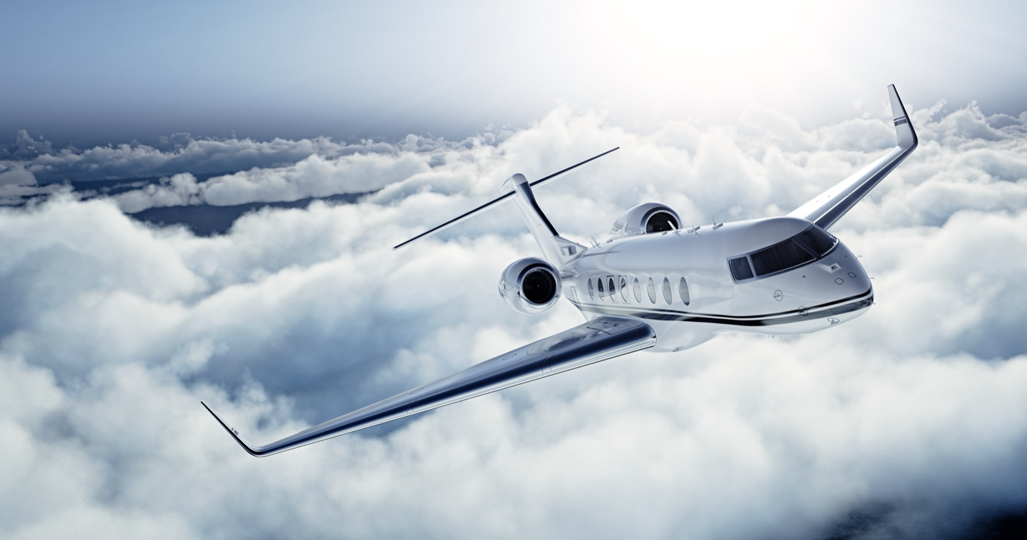 A private jet in flight above a layer of cloud.